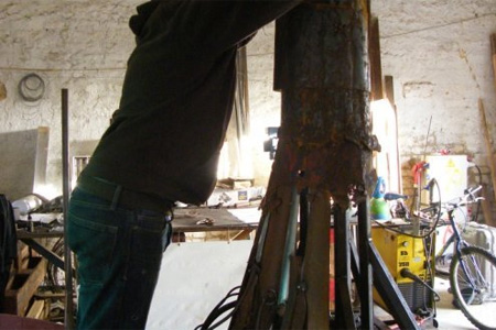 Karlito travaille à sa sculpture monumentale pour La Palène. Un assemblage de diverses pièces de ferraille qui deviendront une oeuvre monumentale de 7 mètres de haut. Photo : C.L.